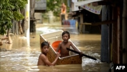 Children use a refrigerator as a boat to cross a flooded alley in Candaba, Pampanga, north of Manila, The Philippines, Dec. 18, 2015.