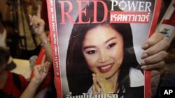 A supporter of Thailand's prime minister-elect Yingluck Shinawatra holds a magazine with her photo on the front cover as they celebrate her victory following the announcement of exit polls at the party headquarter in Bangkok, July 3, 2011