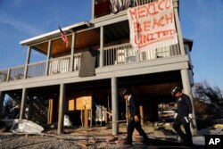 A banner hangs from a damaged home as a South Florida urban search and rescue team checks for survivors of Hurricane Michael, in Mexico Beach, Florida, Oct. 12, 2018.