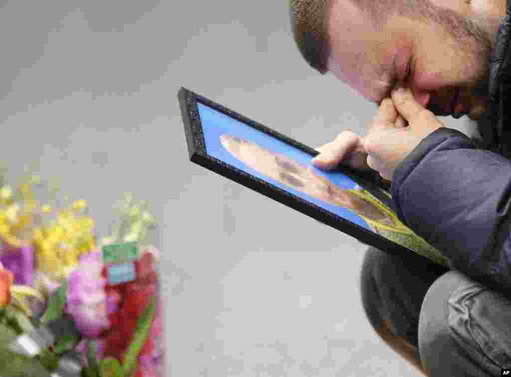 The partner of Julia Sologub, a member of the flight crew of the Ukrainian 737-800 plane that crashed on the outskirts of Tehran, reacts as he holds a portrait of her at a memorial inside Borispil international airport in Kyiv, Ukraine.