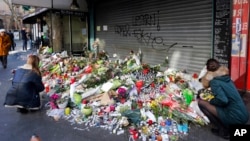 Flowers and candles are placed in front of the restaurant on Rue de Charonne, Paris, Nov. 15, 2015, where attacks took place on Friday. 