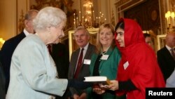 Malala Yousafzai memberikan buku "I Am Malala" pada Ratu Elizabeth dalam sebuah resepsi untuk anak muda, pendidikan dan negara-negara persemakmuran di Istana Buckingham, London (18/10). 