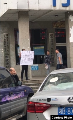 2019年10月22日，邱孝斌在湖南株洲三医院门前举牌声援“泼墨女孩”董瑶琼