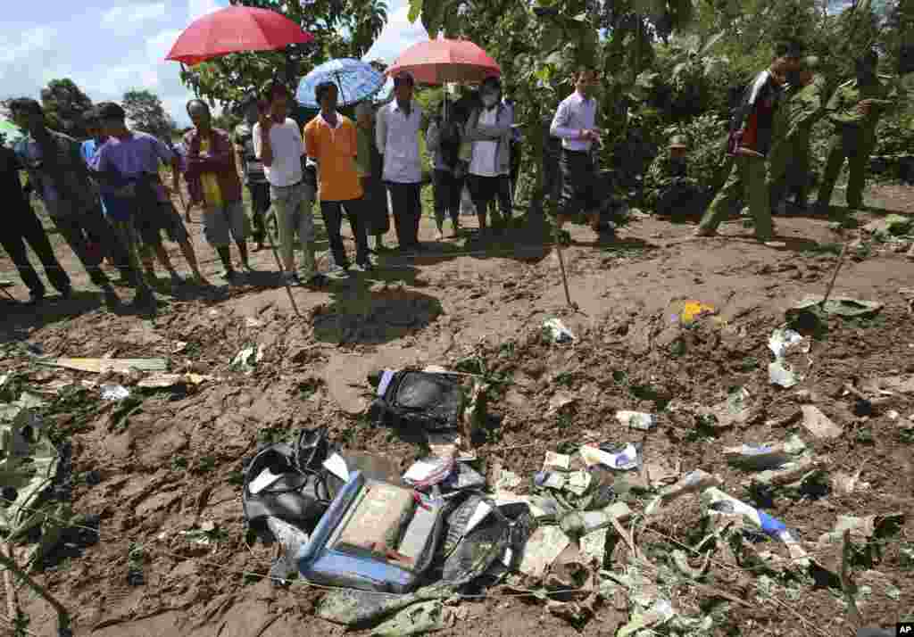 People look at the debris of a Lao Airlines turboprop plane that crashed into the Mekong River, in Pakse, Laos, Oct. 17, 2013. 