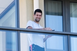 Bintang tenis Novak Djokovic berdiri di balkon tempat dia dikarantina sebelum Australia Terbuka di Melbourne, di Adelaide Utara, Australia, 19 Januari 2021. (Foto: AAP/Morgan Sette via REUTERS)