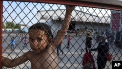 ARSIP – Seorang anak berdiri di balik pagar selama unjuk rasa menentang kondisi kehidupan di kamp Oreokastro, dekat kota Thessaloniki yang terletak di sebelah utara Yunani, tanggal 25 Juni 2016 (foto: AP Photo/Giannis Papanikos)