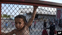 Un enfant debut derrière des barrières lors d'une manifestation sur les conditions de vie dans le camp de Oreokastro, près de la ville de Thessaloniki, Grèce, le 25 juin 2016.