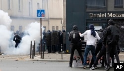 Youth, right, face French riot police officers during the May Day demonstration, May 1, 2017, in Paris. Paris police are firing tear gas at rowdy protesters on sidelines of May Day workers' march.