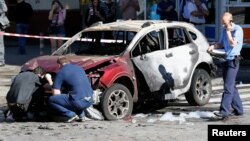 Investigators inspect a damaged car at the site where journalist Pavel Sheremet was killed by a car bomb in central Kyiv, Ukraine, July 20, 2016.