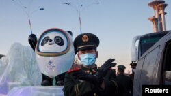 지난 15일 중국 공안이 베이징 시내 동계올림픽 마스코트 조형물 앞에서 손짓하고 있다. 