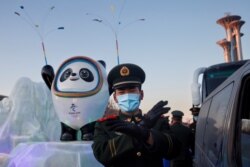 一名中国武警士兵在北京的冬奥会吉祥物前给拍照者做手势。（2022年1月15日）