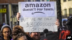 Protesters hold up anti-Amazon signs during a coalition rally and press conference of elected officials, community organizations and unions opposing Amazon headquarters getting subsidies to locate in Long Island City, Wednesday, Nov. 14, 2018, in New York. 