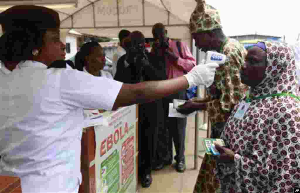 Wani jami’in kula da lafiyar matafiya na amfani da ma’aunin zafin jiki ya na yiwa Maniyyata gwajin cutar Ebola a ranar goma sha takwas ga watan satumba shekarar dubu biyu da goma sha hudu.