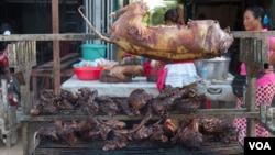 Grilled dog meat are on display at a food kiosk along a street in Phnom Penh. (Neou Vannarin/VOA Khmer) 