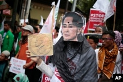 지난해 11월 인도네시아 자카르타 주재 미얀마 대사관 앞에서 열린 '로힝야족 학살 반대' 집회 참가자가 아웅산 수치 미얀마 국가자문역 겸 외무장관의 가면을 쓴 채 노벨평화상 사진을 들어보이고 있다.