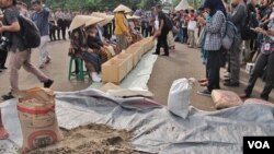 Warga menyaksikan unjuk rasa sembilan perempuan asal Pegunungan Kendeng, Jawa Tengah di depan Istana Negara, Jakarta, Selasa sore 12/4 (VOA/Fathiyah).