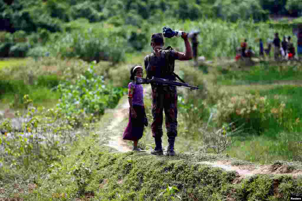 A member of Border Guard Bangladesh (BGB) tells a Rohingya girl not to come on Bangladesh side, in Cox&rsquo;s Bazar, Bangladesh.