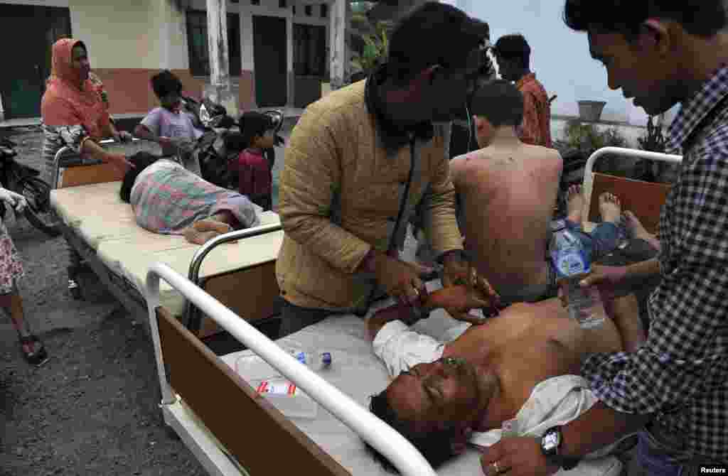 Injured residents receive treatment outside the local clinic after a strong earthquake hit in Bener Meriah district, July 2, 2013. 