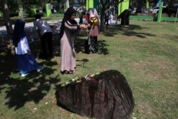 Seorang warga menuangkan air ke sebuah batu yang menandai kuburan massal bagi para korban tsunami Samudra Hindia dalam peringatan 15 tahun bencana di Banda Aceh, Kamis, 26 Desember 2019. (Foto AP / Nurhasanah)
