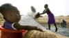 FILE - Mariama Diokh throws salt onto a pile while her 5-month-old infant sits in a nearby basket on the Senegalese coast close to the Gambian border in June 2006. 