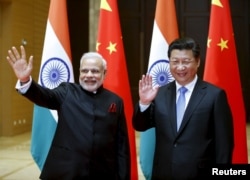 FILE - Indian Prime Minister Narendra Modi (L) and Chinese President Xi Jinping wave to journalists before they hold a meeting in Xian, Shaanxi province, China, May 14, 2015.