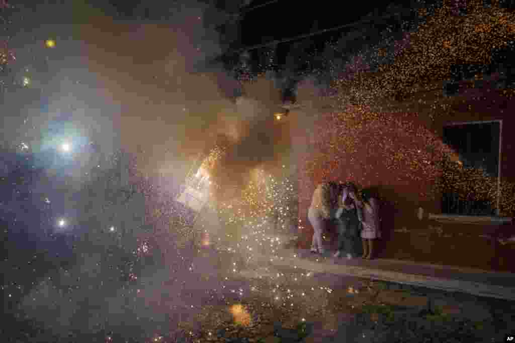 People cover themselves in front of a man wearing a &quot;torito,&quot; a bull-shaped harness equipped with fireworks, during a Christmas celebration in Antigua, Guatemala, Dec. 25, 2021.