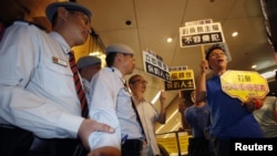 Protesters chant slogans in front of security guards inside building where Japanese Consulate is located in Hong Kong, August 15, 2012.