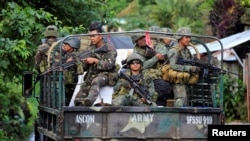 FILE - Government soldiers fill a military truck as they continue their assault on insurgents from the Maute group, who have taken over large parts of Marawi City, Philippines, June 1, 2017. 