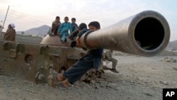 FILE - Afghan children play on the remains of a Soviet tank in the Behsood district of Jalalabad, Afghanistan, Feb 18, 2013. 