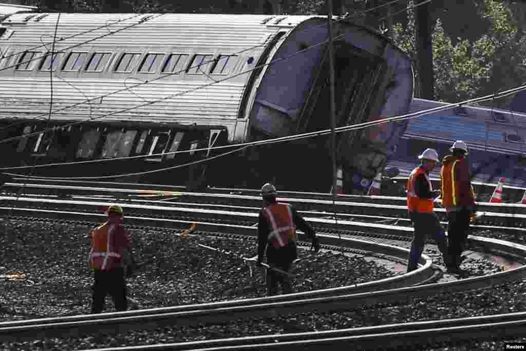 Para pejabat melakukan survei di lokasi kereta api Amtrak yang anjlok di Philadelphia (13/5). ​(Reuters/Mike Segar)