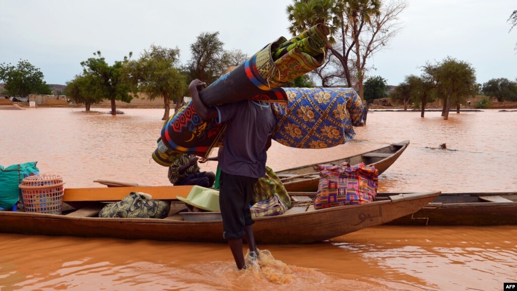 FILE - Ein Mann trägt seine Sachen zu einem Boot während der Überschwemmung in einem Bezirk in Niamey, Niger, 5. September 2013. 