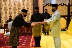 Perdana Menteri Malaysia Ismail Sabri Yaakob (kiri) menerima dokumen dari Raja Sultan Abdullah Sultan Ahmad Shah sebelum mengambil sumpah sebagai pemimpin baru negara itu di Istana Nasional Malaysia, Kuala Lumpur, 21 Agustus 2021. ((Khirul Nizam Zanil/Malaysia's Department of Information via AP)