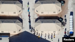 Immigrant children, many of whom have been separated from their parents under a new "zero tolerance" policy by the Trump administration, are shown walking in single file between tents in their compound next to the Mexican border in Tornillo, Texas, June 18, 2018.