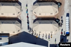 FILE - Immigrant children, many of whom have been separated from their parents under a new "zero tolerance" policy by the Trump administration, are shown walking in single file between tents in their compound next to the Mexican border in Tornillo, Texas, U.S.,