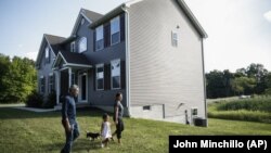 Joyce Lilly, right, holds her granddaughter Paige's hand alongside her husband, Anil, and dog Max at their new home, Tuesday, July 21, 2020, in Washingtonville, New York. (AP Photo/John Minchillo)