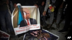Un palestino sostiene un cartel con la foto del presidente de EE.UU., Donald Trump, durante protestas contra el plan de paz estadounidense en Belén, el lunes, 27 de enero de 2020.