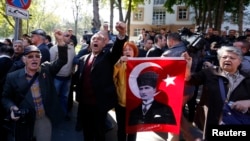 FILE - Relatives of detained military officers hold a portrait of Mustafa Kemal Ataturk, founder of modern Turkey, shouting slogans in front of a courthouse in Ankara, Oct. 9, 2013. 