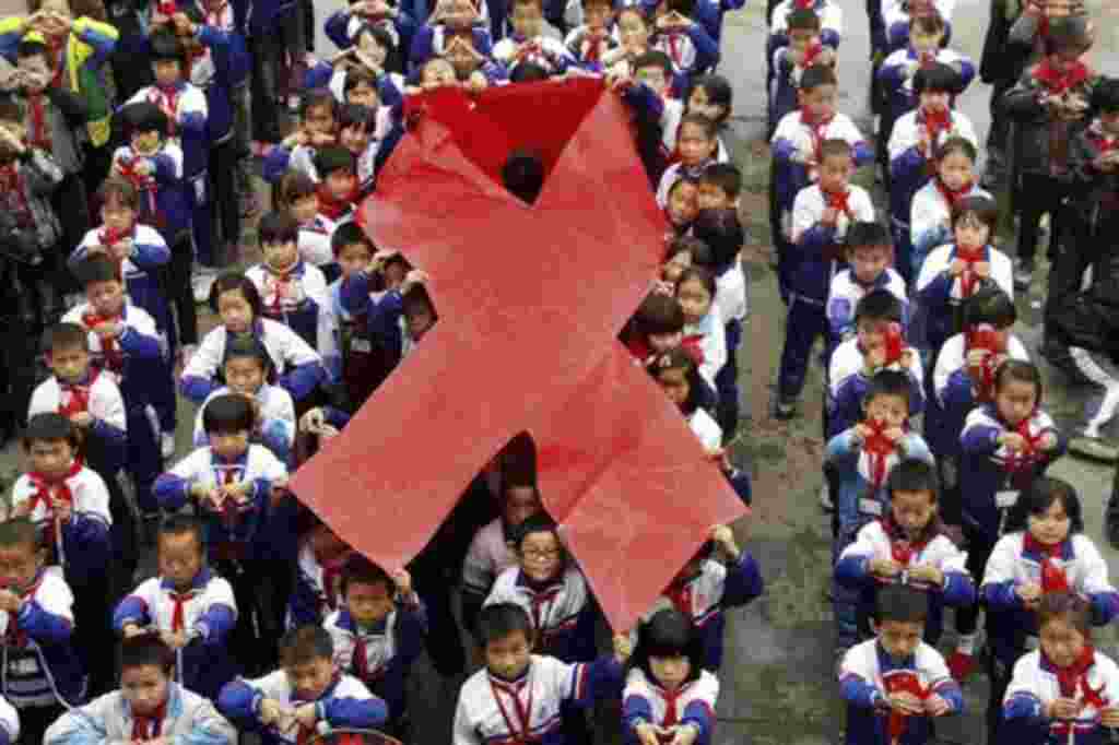 Los estudiantes de primaria presentan lazos en un evento en la víspera del Día Mundial del SIDA en Wuyuan, en la provincia china de Jiangxi. China tendrá cerca de 780.000 personas infectadas con el virus del SIDA a finales de 2011.