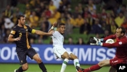 Australia's goalkeeper Mark Schwarzer (R) saves a strike from Saudi Arabia's Naif Ahmed Hazazi (C) as Australia's Lucas Neill watches during their World Cup qualifier soccer match at AAMI Park in Melbourne, February 29, 2012.