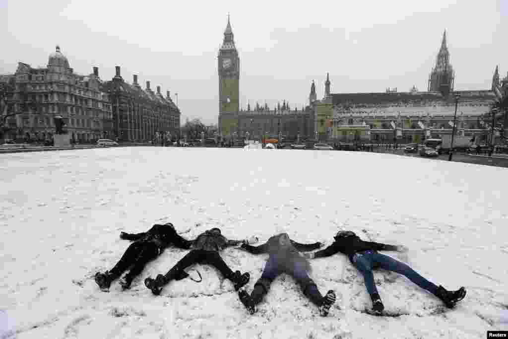Bốn người trẻ nằm vẽ hình thiên thần trên tuyết tại Quảng trường Quốc hội gần Hạ viện tại Trung tâm London. Một trận tuyết dày dặc ảnh hưởng hầu hết nước Anh vào ngày thứ Sáu, mang rối loạn trên đường phố. và gây ra cúp điện và trường học đóng cửa. (Reuters) 