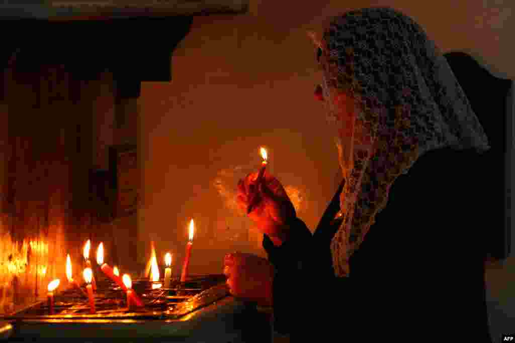 A Syrian Christian woman lights candles during a Good Friday mass at the Syriac church of the Holy Virgin in the northeastern city of Qamishli, during Easter celebrations.