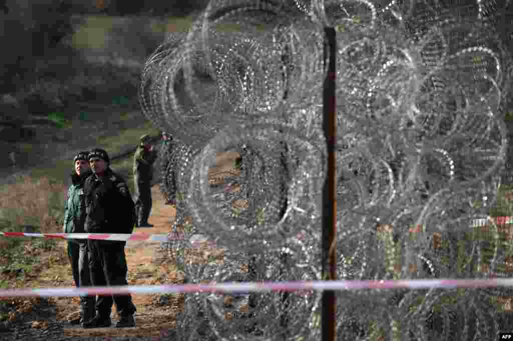 Polisi perbatasan berjaga-jaga di samping pagar kawat duri sepanjang perbatasan Bulgaria dan Turki, 28 November 2013. Pagar kawat yang sedang dibangun ini akan terentang sepanjang sekitar 30 km di perbatasan yang paling sulit dijaga.