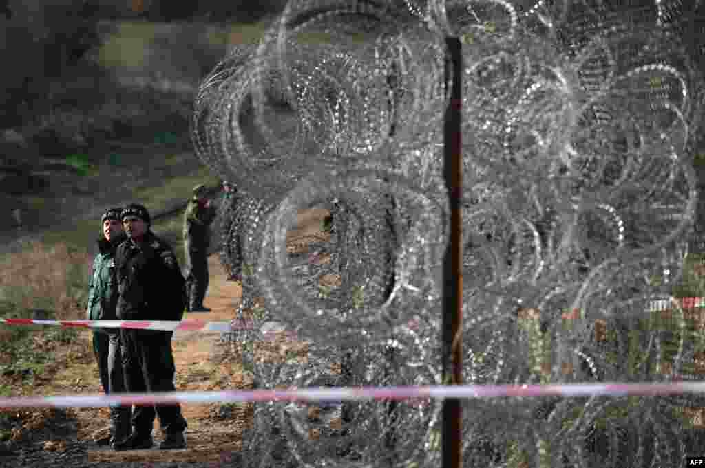 Border police stand guard next to a border fence being built on the Bulgarian border with Turkey, near the village of Golyam Dervent. Bulgaria, the European Union&#39;s poorest member, has been overwhelmed by the arrival this year of almost 10,000 refugees, 60 percent of them Syrians fleeing civil war crossing over illegally from Turkey.