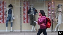 A shopper walks past a clothing shop display on a shopping street in Tokyo Monday, Feb. 15, 2016.