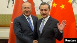 Chinese Foreign Minister Wang Yi, right, shakes hands with Turkish Foreign Minister Mevlut Cavusoglu during their meeting at Diaoyutai State Guesthouse in Beijing, China, Aug. 3, 2017. 