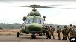 In this photo taken from video released by the Belarusian Defense Ministry Press Service on Nov. 12, 2021, Russian and Belarusian paratroopers load into a military helicopter near the border with Poland.