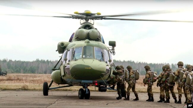 In this photo taken from video released by the Belarusian Defense Ministry Press Service on Nov. 12, 2021, Russian and Belarusian paratroopers load into a military helicopter near the border with Poland.