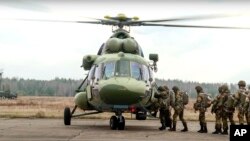 En esta foto tomada de un video publicado por el Servicio de Prensa del Ministerio de Defensa de Bielorrusia el 12 de noviembre de 2021, paracaidistas rusos y bielorrusos suben a un helicóptero militar cerca de la frontera con Polonia. 