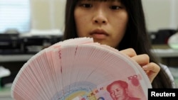 An employee counts Chinese yuan notes inside a bank in Taipei, Feb. 6, 2013.