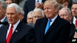 President Donald Trump smiles as Vice President Mike Pence speaks during an event on the South Lawn of the White House in Washington, Dec. 20, 2017, to acknowledge the final passage of tax overhaul legislation by Congress.